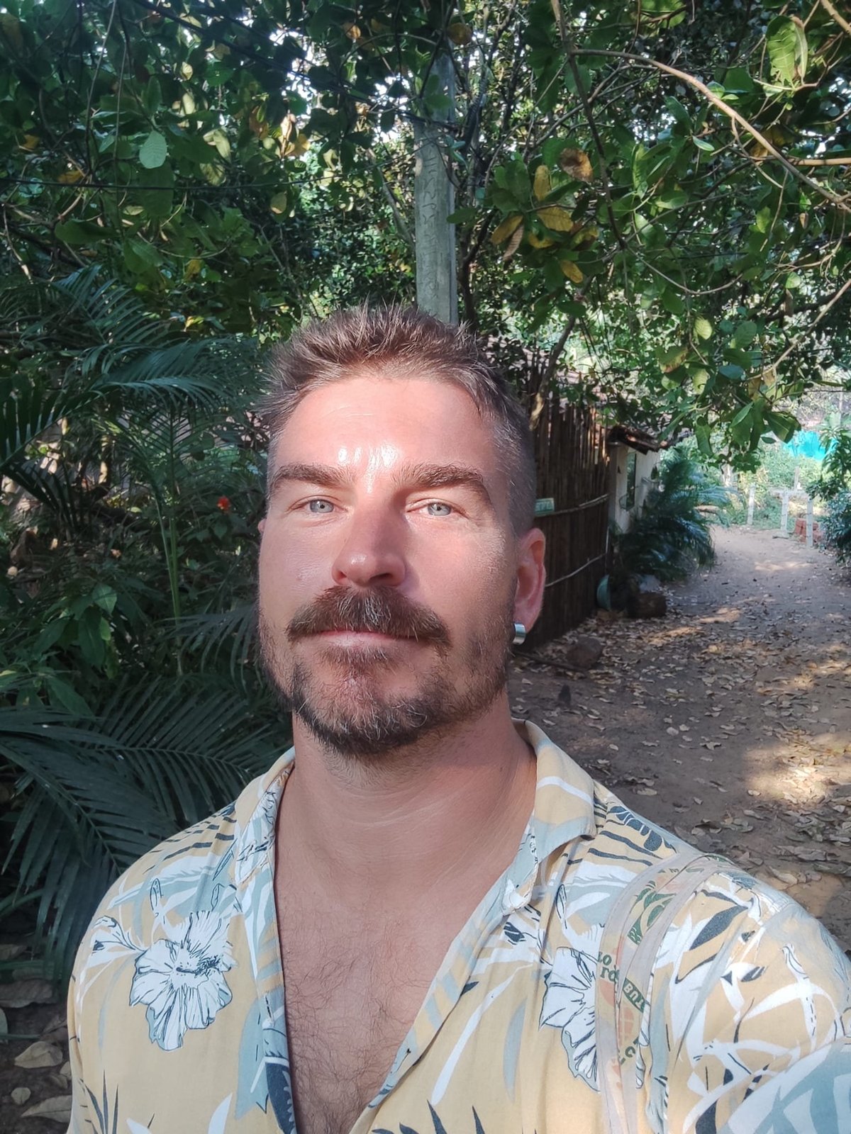 Coach Phill Terp in a tropical garden setting, wearing a light floral shirt